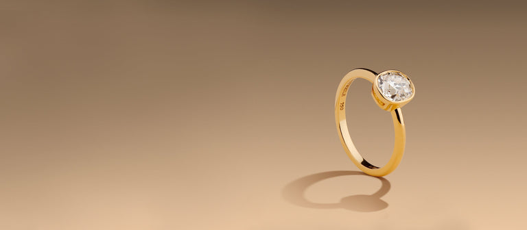 bezel setting solitaire gold engagement ring set with an antique old mine cushion diamond