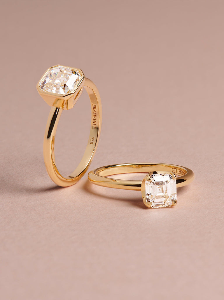 classic solitaire engagement rings in gold set with antique diamonds loose on a surface